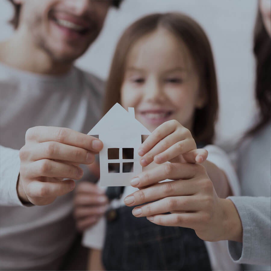 Famille avec projet immobilier tenant une façade de maison en papier